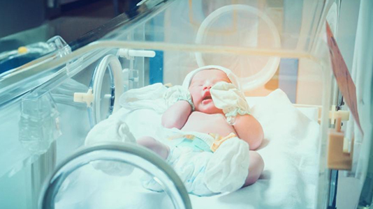 A newborn baby in a hospital incubator